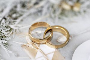 Two gold wedding rings on top of a wedding favour